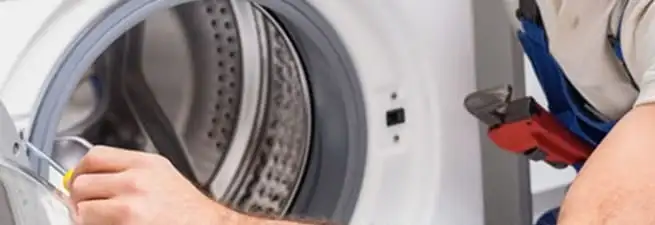 Appliance technician repairing a clothes dryer drum and internal parts in Tucson, AZ