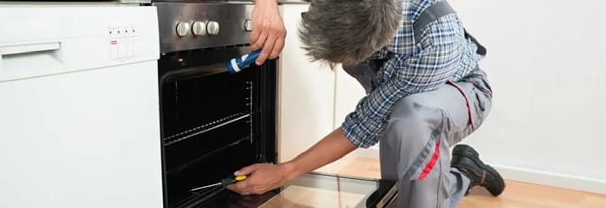 Oven repair technician inspecting and servicing an electric oven in Tucson, AZ